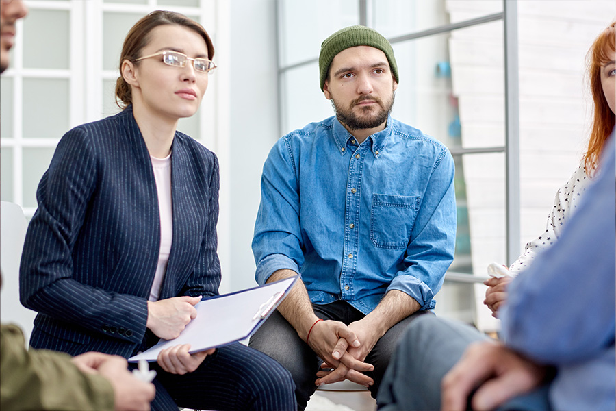 white woman with blonde standing up to share in a support group meeting