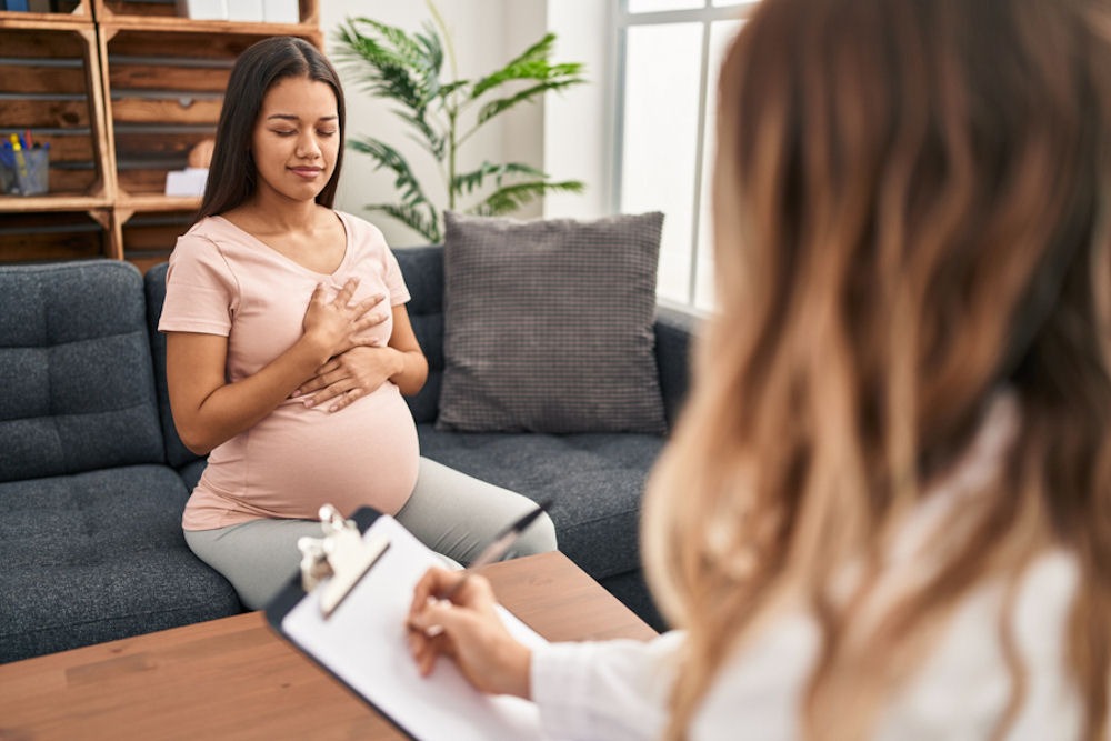 cbt-for-addiction-treatment Pregnant woman closing eyes in CBT session with therapist taking notes, cbt for addiction recovery