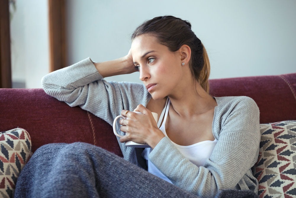 cbt-techniques-in-addiction-recovery a woman sitting in a sofa holding a mug, bipolar and addiction treatment