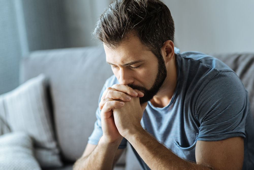 Man leaning forward to rest head on his hands in frustration.
