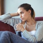 a woman sitting in a sofa holding a mug